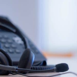 close up on headset with telephone devices at office desk for customer service support concept