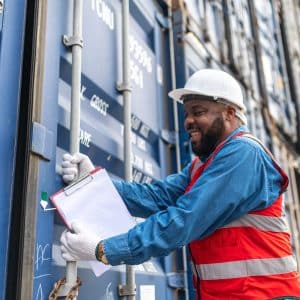 Photo of a black african engineer using his hands trying to open the chain on a container in a shipping containers yard